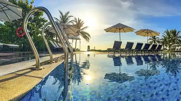 Luxury resort pool with sun loungers and palm trees at sunrise