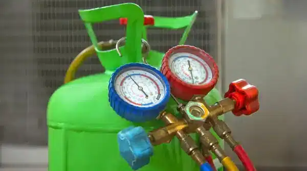 Green refrigerant cylinder with pressure gauges and hoses