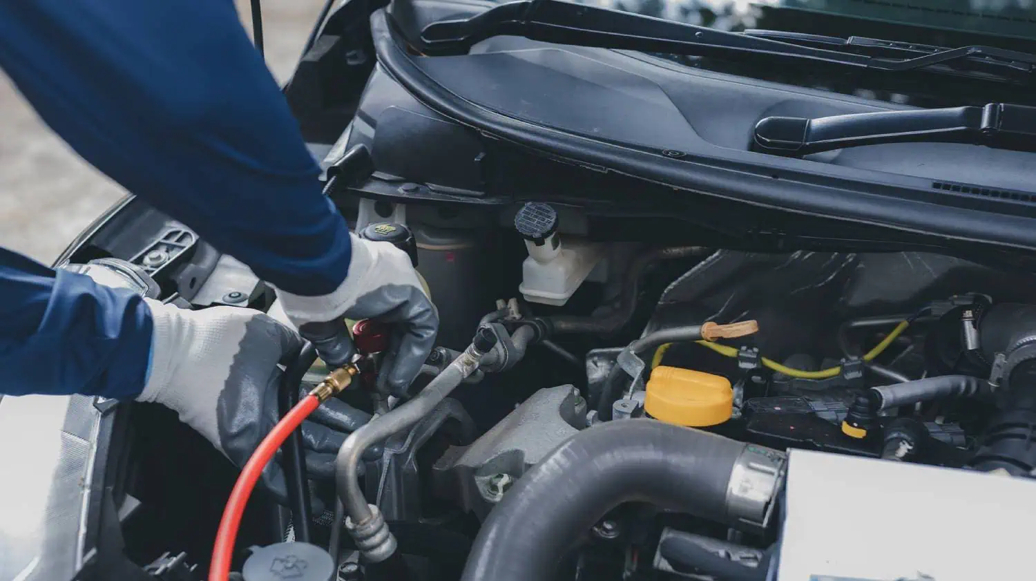 Gloved technician repairing a car engine with tools
