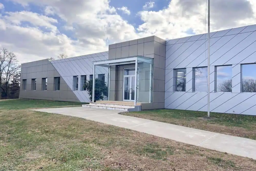 Modern building with a glass entrance and angular exterior design, set against a cloudy sky. Modern building with a glass entrance and angular exterior design, set against a cloudy sky.